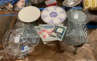 Six-section clear plastic server, Lenox cream and gold platter, glass and ceramic Seder plate, and four vintage Haggadah books arranged on a table.