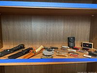 Shelf with various knives and cutters arranged including large knives, folding knives, and sheaths