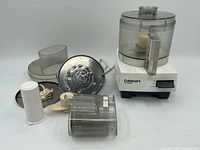 Photo of Cuisinart Pro Classic food processor base unit with various attachments spread around including bowl, lid, slicing/shredding disc, dough blade and pusher.