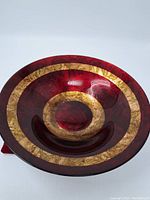 Top view of vintage red glass bowl with large gold leaf rings inside.