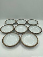 Eight matching vintage Denby soup bowls arranged in two rows showing front top view, displaying beige and brown rim design.