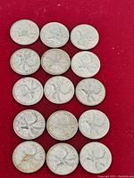 Photo showing all 14 Canadian silver quarter coins arranged on red background, all with visible caribou on reverse.