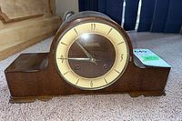 Front view of the Forestville wood mantle clock on carpet showing clock face and body.