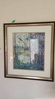 Frontal view of first framed print showing a woodland scene with tall trees and soft color palette.