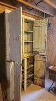 Front angled view of large wooden jam cabinet showing multiple shelves and open doors with peeling white paint.