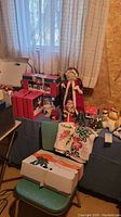 Wide view of holiday decorations including Santa figurines, holiday boxes, embroidered cloths, and a green chair with boxes