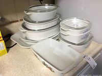All cookware items stacked and arranged showing various pieces and lids including platters and casserole dishes.