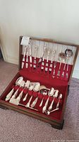 Full view of the W M Rogers Victorian Rose silverplate cutlery set displayed in the wooden box with red felt lining, showing all pieces organized in slots.