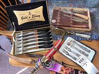 Full lot view including Gold 'n Ebony Steakmaster steak knives, boxed wooden knife set, silver serving utensils, decorative fork and carving knife, and scissors.