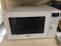 Front view of Panasonic white microwave oven with digital display and control panel on the right side.
