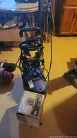 Blue and black Simoniz pressure washer from front view showing base, handle, accessories wrapped around