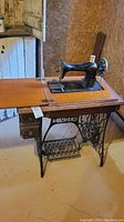 Full view of the vintage Singer sewing machine mounted inside a wooden table with one fold-out extension leaf.