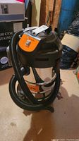 Full view of Kubota shop vacuum cleaner showing stainless steel body, black top, and attached hose.