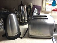 Photo showing Cuisinart toaster, Black and Decker kettle, and Presto coffee percolator together on countertop