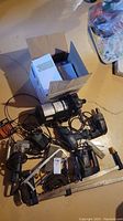Photo showing multiple assorted tools on floor including electric saws, drills, clamps and boxed items.