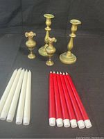 Four brass candle holders and ten battery powered LED candles arranged on a black background, showing the overall lot