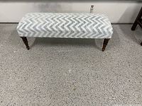 Full view of the upholstered bench showing chevron pattern fabric and overall shape.