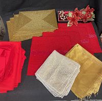 Christmas table decor including placemats, napkins, napkin rings, tablecloths, and tray arranged on black background.