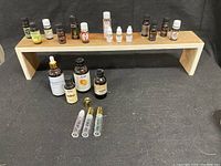 Full view of essential oil bottles arranged on two wooden shelves, includes dropper bottles and rollerball applicators.