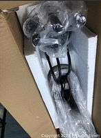 Chandelier chain and mounting hardware wrapped in plastic and secured in packaging.