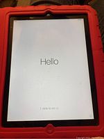 Apple iPad 2 tablet in red kidproof case showing initial 'Hello' setup screen.