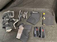Photo showing various knee braces and support straps arranged on a black surface.