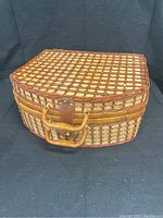 Closed wicker picnic basket with latch and handle on black background