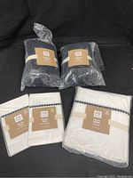Photo of 6 bedding pieces in original packaging including 2 black crinkle puff Euro shams and 4 white pop dot shams and bedskirts with black dots.