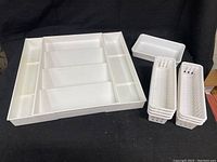 White expandable spice drawer organizer with sliding sides and five compartments shown from an angled view with additional small organizing bins beside it.
