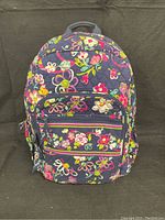 Front view of large Vera Bradley backpack in floral Ribbons pattern with one front zip pocket and padded shoulder straps.