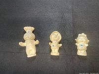 Photo showing the three Pillsbury Doughboy family figurines, standing on black surface, front view.