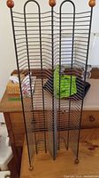 Metal CD display rack with wooden ball tops and multiple slots for CDs or DVDs.