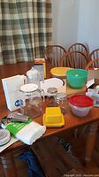 Photo of table showing chopping boards, plastic containers, glass pitchers, mini food chopper, and other kitchen items