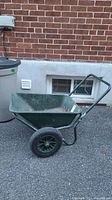 Side view of green Yardworks wheelbarrow with metal bucket and one inflatable tire.