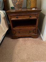 Front view of Aspen Home nightstand showing two drawers with dark metal hardware and open middle shelf.