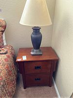 Nightstand with lamp on top next to sofa, showing full nightstand and lamp in corner