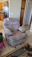 Beige cloth recliner chair placed on tiled floor in a kitchen setting, showing full frontal view to highlight size and shape.