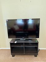 Front view of Samsung 46-inch television on black media stand, remote visible.