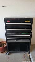Full view of the black Stanley two-piece toolbox on wheels showing multiple drawers and open storage bottom.