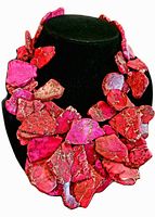 Front view of chunky jasper necklace displayed on black stand, showing large pink and red veined stone pieces.
