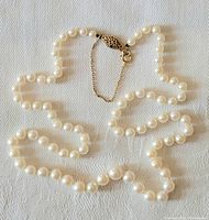 Full view of white freshwater pearl necklace showing length and graduated pearls with 10K gold clasp.