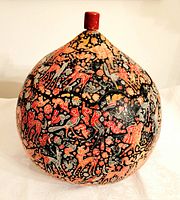 Front view of the large carved gourd box showing the detailed painted animal and bird designs and the red handle on the lid.