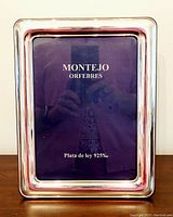 Front view of the Montejo sterling silver photo frame with a reflective polished silver surface and placeholder card indicating hallmarked silver .925 purity.