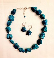 Full view of the turquoise nugget necklace with matching earrings laid flat against a light surface showing the natural stone color and shape.