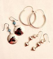 Three pairs of sterling silver earrings displayed together on white fabric background.