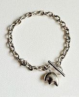 Front view of sterling silver chain bracelet showing entire loop and attached polar bear paw charm with toggle clasp.