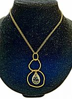 Gold-tone chain necklace with an abstract-shaped pendant and a central teardrop smoky faceted stone displayed on black velvet bust.
