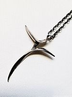 Close-up of stylized pewter cross pendant showing design details and chain attachment.