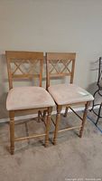 Two wood grain bar stools with cloth covered seats visible, showing full height and seat area.