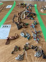 Photo of multiple beaded jewelry items including necklaces, bracelets, and earrings spread out on a wooden surface with a MaxSold tag